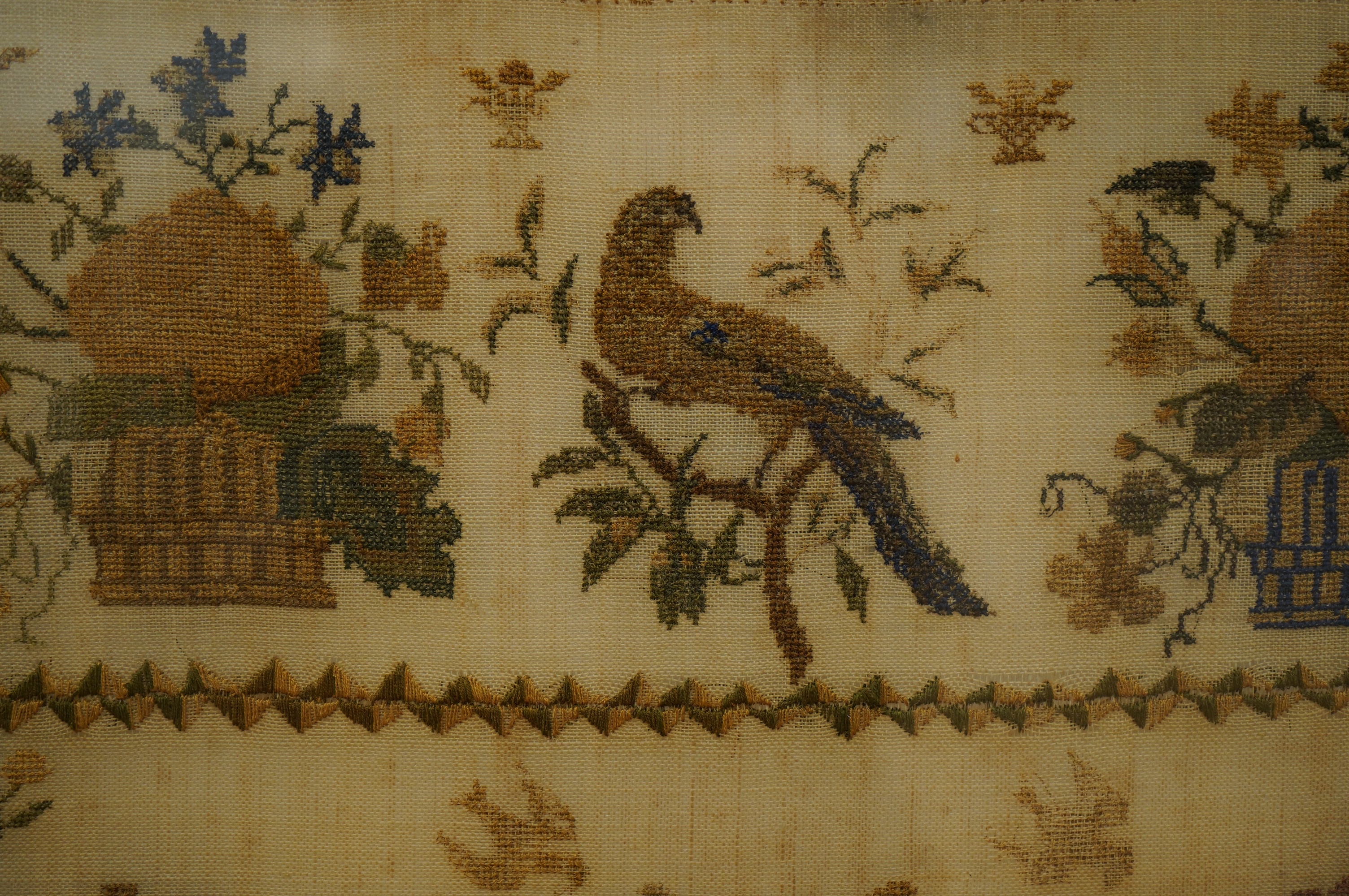 A rosewood framed sampler, dated 1842, by Martha Brook, aged 11years, worked above with large motifs of flower baskets and a bird, a vase of flowers beneath, surrounded by crowns, butterflies and chicks above two small c